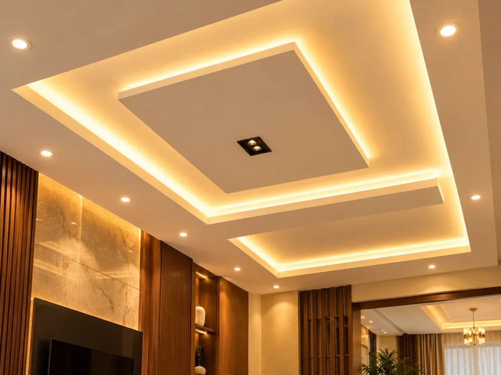 Layered false ceiling with cove lighting and recessed lights